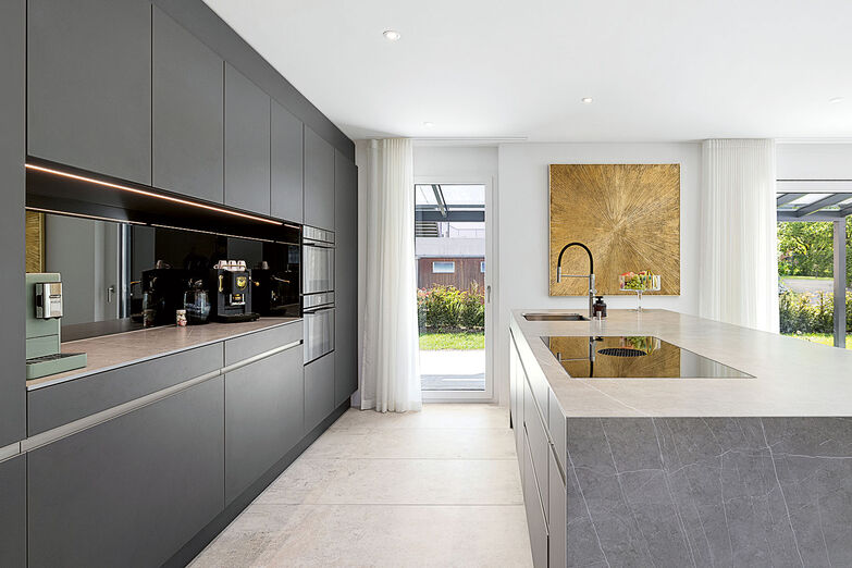 Die dunkle Küchenfront ist ein schöner Kontrast zum hellen Steinboden.