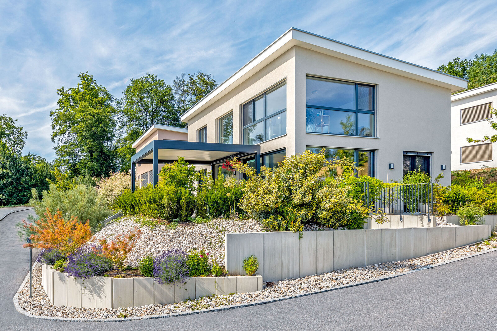 Auf dem Eckgrundstück ist das moderne Einfamilienhaus mit Pultdach optimal an den Hang angepasst.