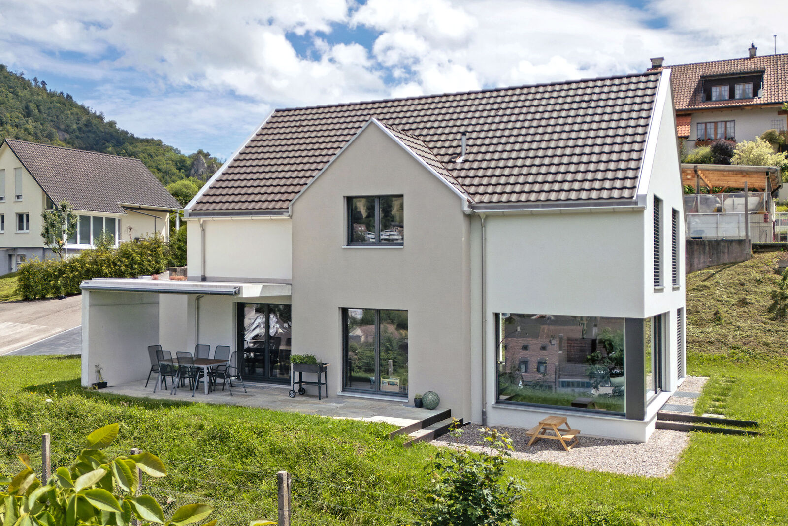 Das Einfamilienhaus überzeugt mit klaren Linien, kontrastreicher Fassadengestaltung sowie einem Satteldach und fügt sich stimmig in die Umgebung ein.