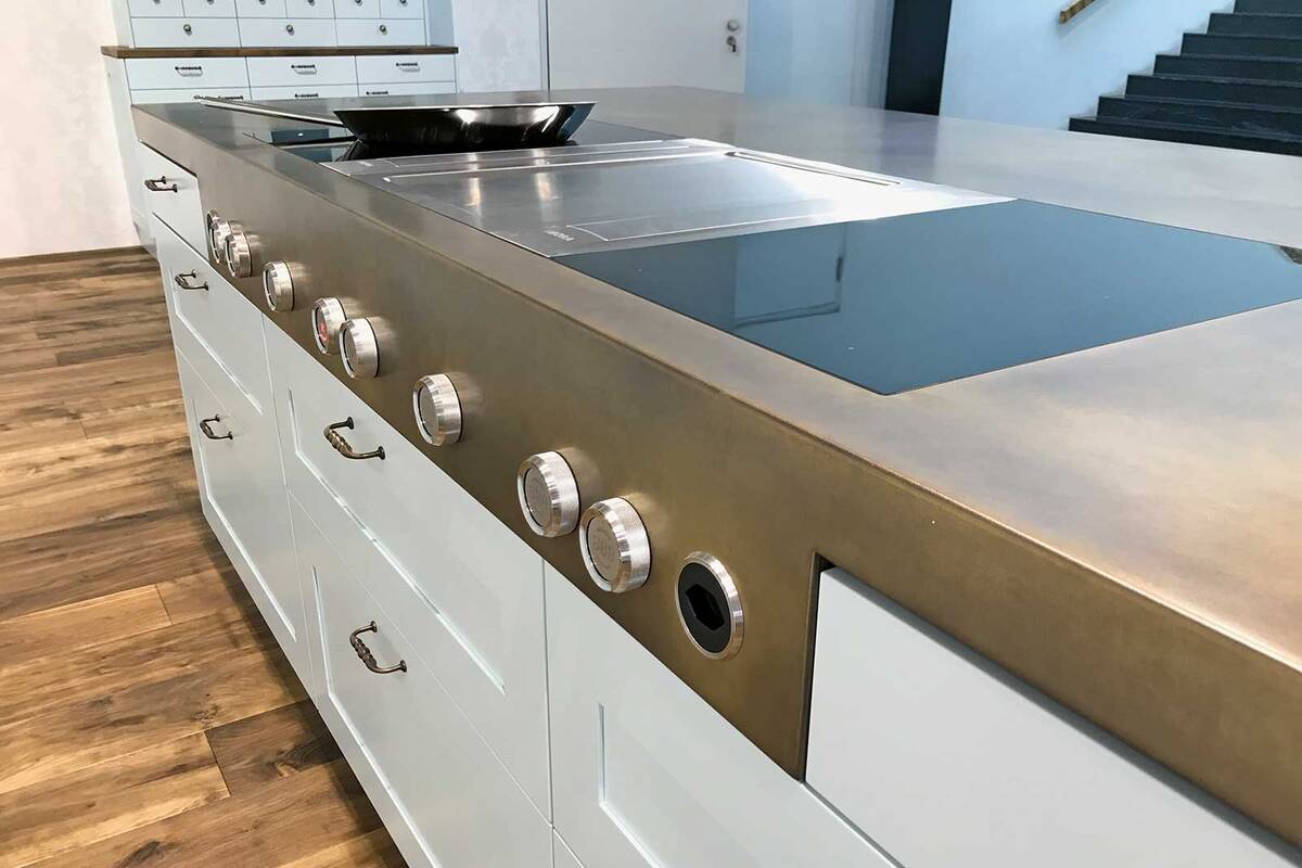 Wenn es um Metall in verschiedenen Formen und Grössen geht, so sind der Fantasie und Kreativität (fast) keine Grenzen gesetzt. Diese Arbeitsplatte aus Messing ist mit einem Wirbelfinish patiniert, und eine angeschweisste Blende mit Bedienknebel setzt elegante Akzente. Merial AG.