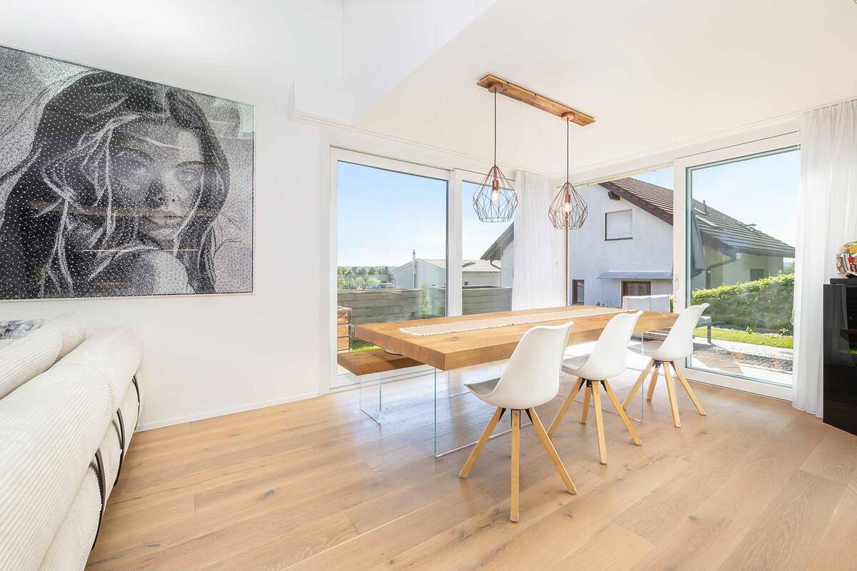 Der massive Holztisch und die Sitzbank wirken mit den Beinen aus Glas fast schwebend.