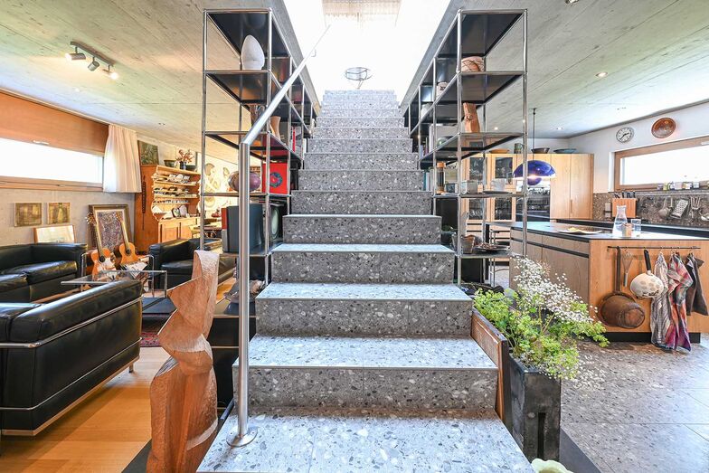 Die Treppe aus widerstandsfähigem Terrazzo bildet ein zentrales Gestaltungselement und setzt einen markanten architektonischen Akzent.
