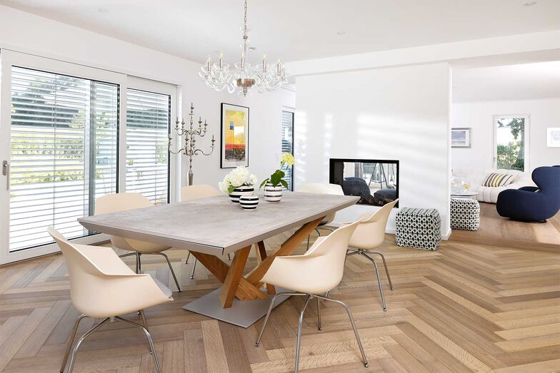 Das Haus zeichnet sich durch eine klare architektonische Sprache aus: offen, hell, mit viel Licht und bodentiefen Fenstern. Einen besonderen Blickfang stellen die ausgewählten Möbel- und Dekostücke sowie die Wand mit dem integrierten Kamin dar.