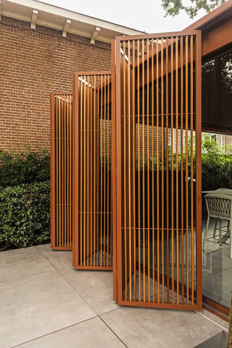 Wieso den Sichtschutz nicht gleich mit dem Sonnenschutz oder einer Überdachung kombinieren? ­Renson realisierte diesen Outdoorbereich. Die ruhigen Erdtöne und die natürlichen Materialien wirken elegant. Die klaren Linien strahlen Ruhe aus. Glasschiebetüren, Beleuchtungsarmaturen und faltbare Loggia-Paneele vervollständigen das Bild. www.renson.net