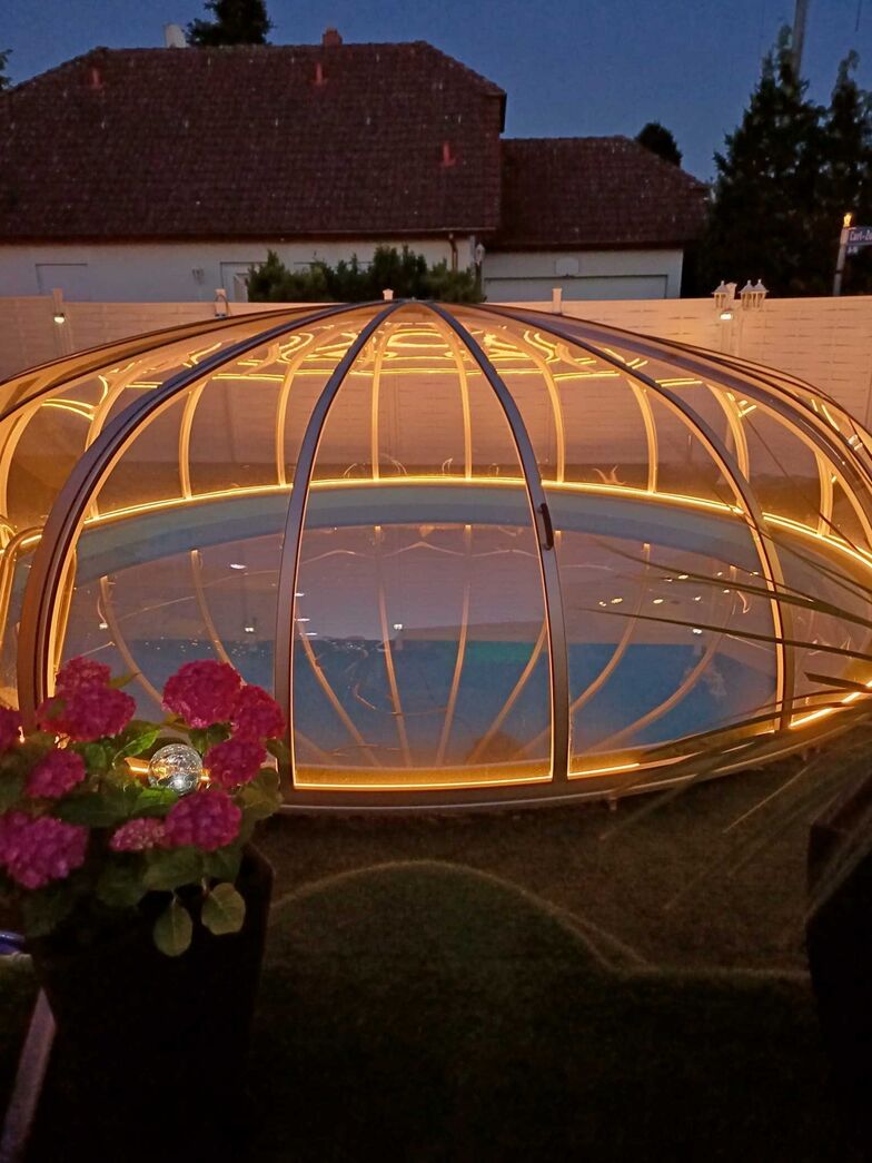 Eine Poolüberdachung verlängert die Badesaison und hat auch sonst viel zu bieten. Die Ambiente-Beleuchtung sorgt beispielsweise für eine besondere Stimmung und es stehen verschiedene Farbmodi zur Auswahl. Das Modell «Rund» ist äusserst stabil und die Doppeltür ermöglicht eine maximale Öffnung bis nahezu zur Mitte. Der Durchmesser beträgt hier circa 6,5 Meter.