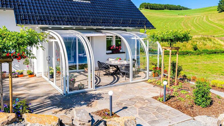 Die gebogene, transparente Dachfläche der Solarveranda «Saphir» bietet einen freien Blick nach draussen. Die Sonnenstrahlen werden gebündelt und verstärkt nach innen geleitet. So wird es im Winter, selbst bei Minusgraden, schnell angenehm warm – ganz ohne Heizung. Bei entsprechenden Aussentemperaturen kann die Glasüberdachung weit geöffnet werden, sodass sich die Veranda in einen Freisitz verwandelt.