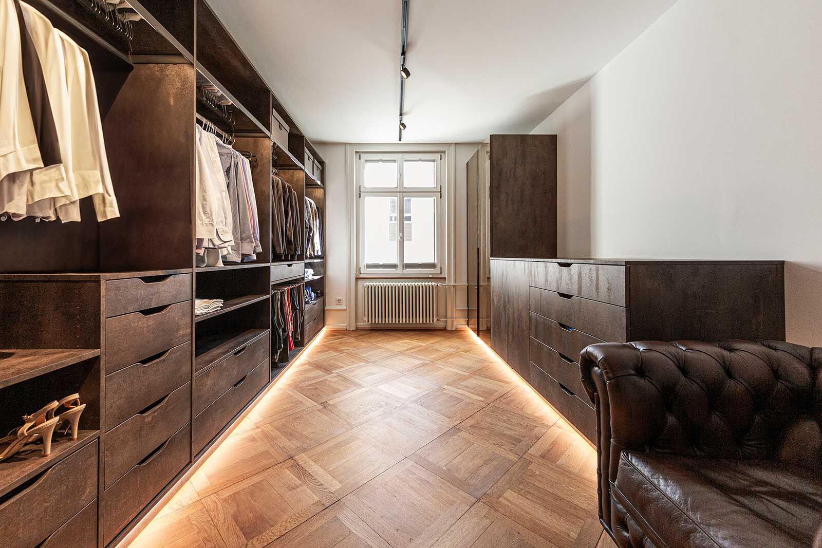 In dieser begehbaren Ankleide reiht sich Schrank an Schrank passgenau und bietet in Schubladen und hinter Schiebetüren zusätzlichen Stauraum.