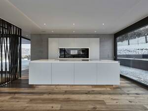 Die grifflosen Fronten unterstreichen den minimalistischen Stil der Küche. Bei der schwebend wirkendenden Arbeitsplatte handelt es sich um den Kunststein «Silestone Blanco Zeus». Furrer Küchen AG.