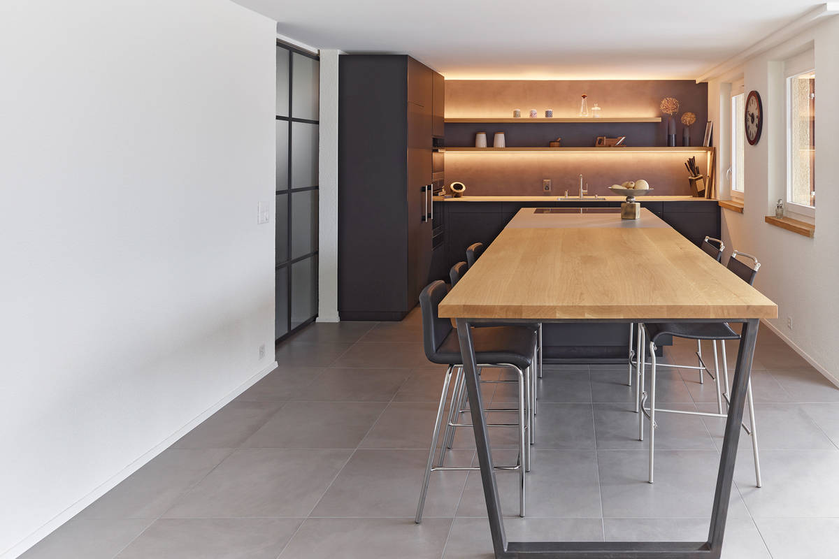 Eichenholz, gespachelte Rückwände, Metallelemente und Edelstahlabdeckungen – so geht die moderne Küche mit gemütlichem Charakter. Oesch Innenausbau.
