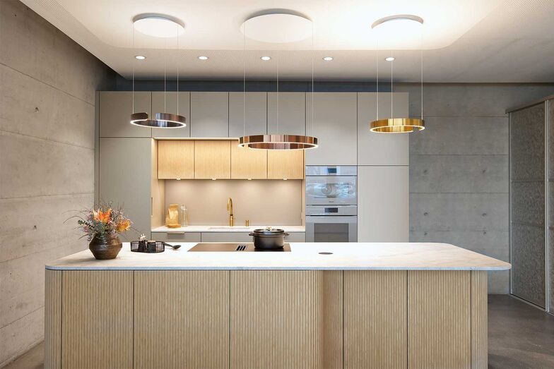 Aufeinander abgestimmt: Diese Wohnküche befindet sich im Showroom der Schreinerei Fehlmann AG in Müllheim. Die Front aus Eiche mit Reliefstruktur verleiht der Küche einen edlen natürlichen Look. Die Aussenlackierung und das Griffprofil harmonieren mit dem Backofen und Combi-Steamer in Pearlbeige. Durch die formverleimten Fronten wird der Stauraum hinter den Rundungen effizient genutzt. Das matte Induktionskochfeld von Miele mit besonderer Struktur und Anti-Fingerprint-Effekt sorgt für eine makellose Optik.   Schreinerei Fehlmann AG, www.schreinerei-fehlmann.ch